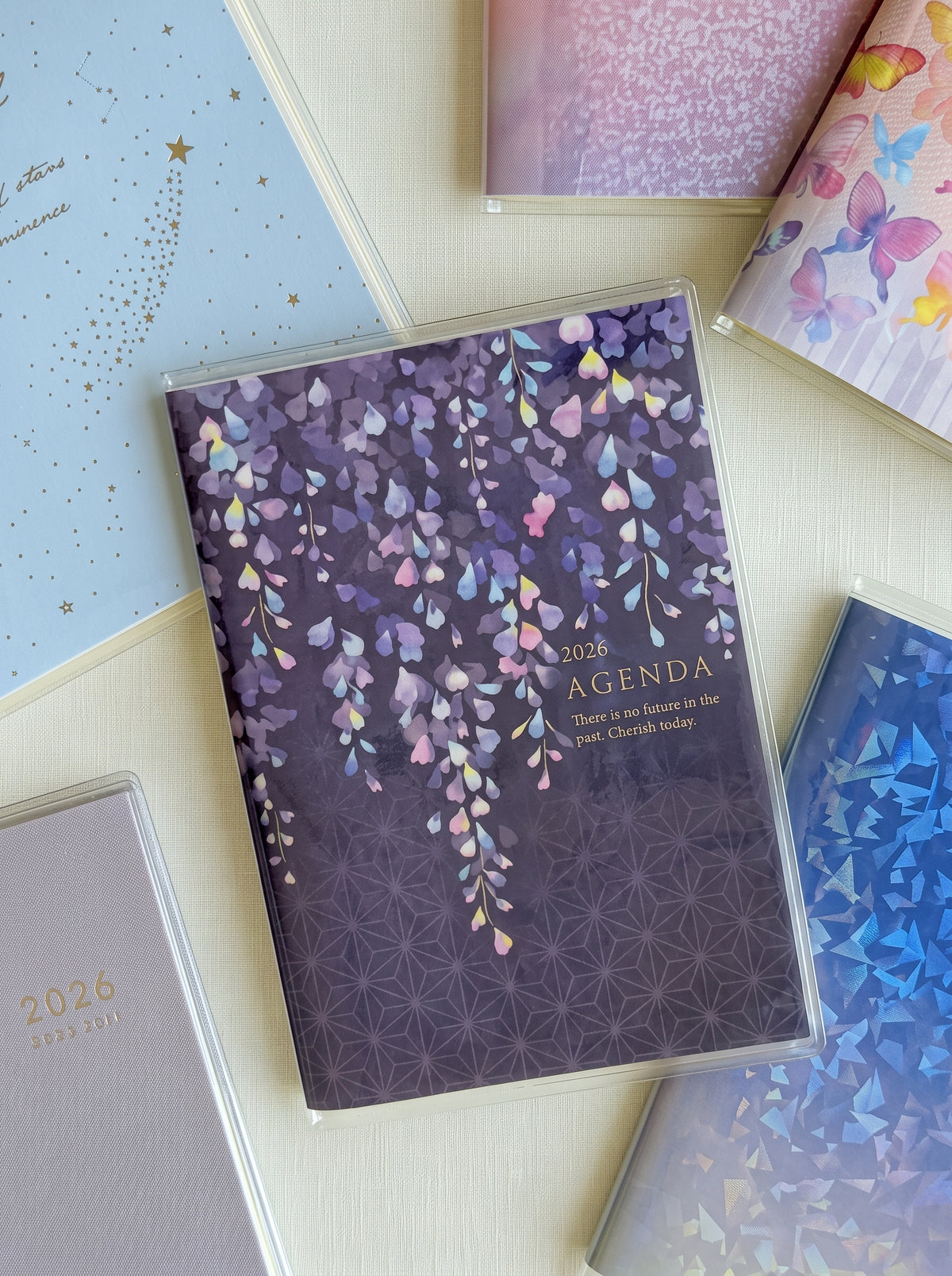A6 monthly agenda planner by JapanoMono with wisteria cover design, displaying open pages for April 2026 to May 2027.