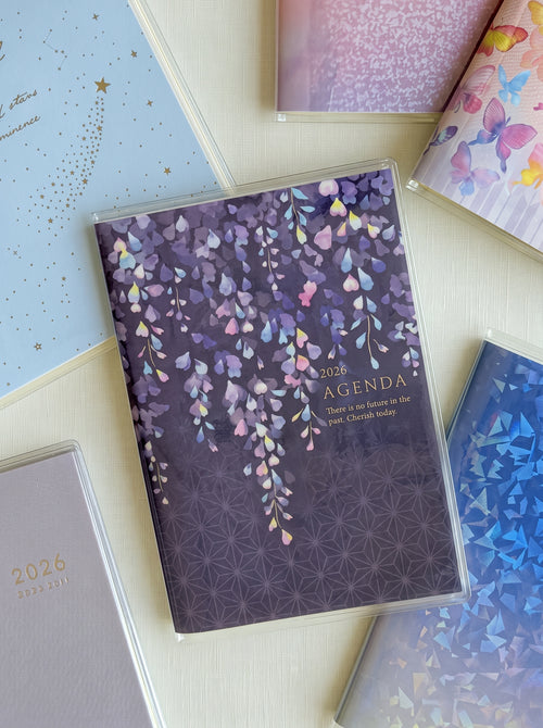A6 monthly agenda planner by JapanoMono with wisteria cover design, displaying open pages for April 2026 to May 2027.