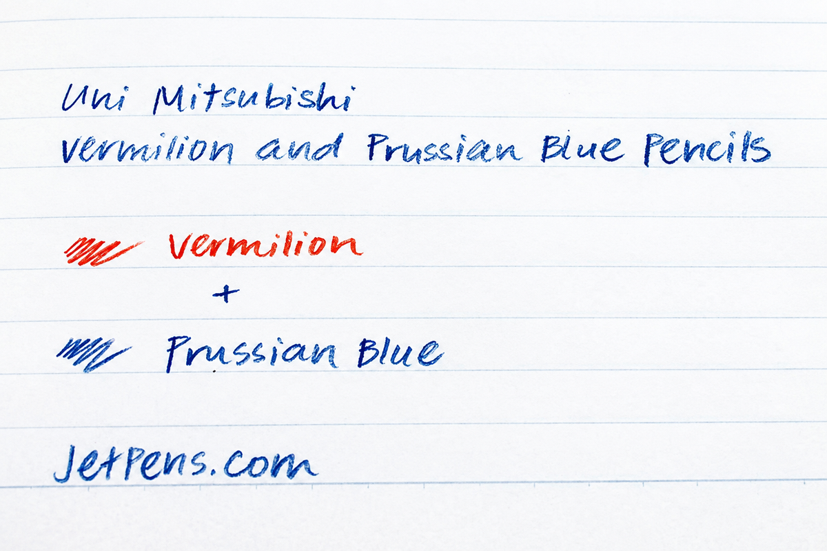 Uni Mitsubishi coloured pencils in vermillion and Prussian blue, featuring round shape and vibrant pigment, on textured paper.