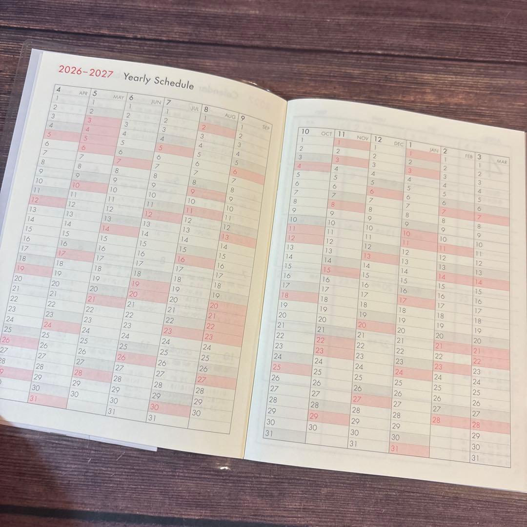 A6 Monthly Agenda Planner by JapanoMono with wisteria cover design for 2026-2027, showing open pages with date layouts.